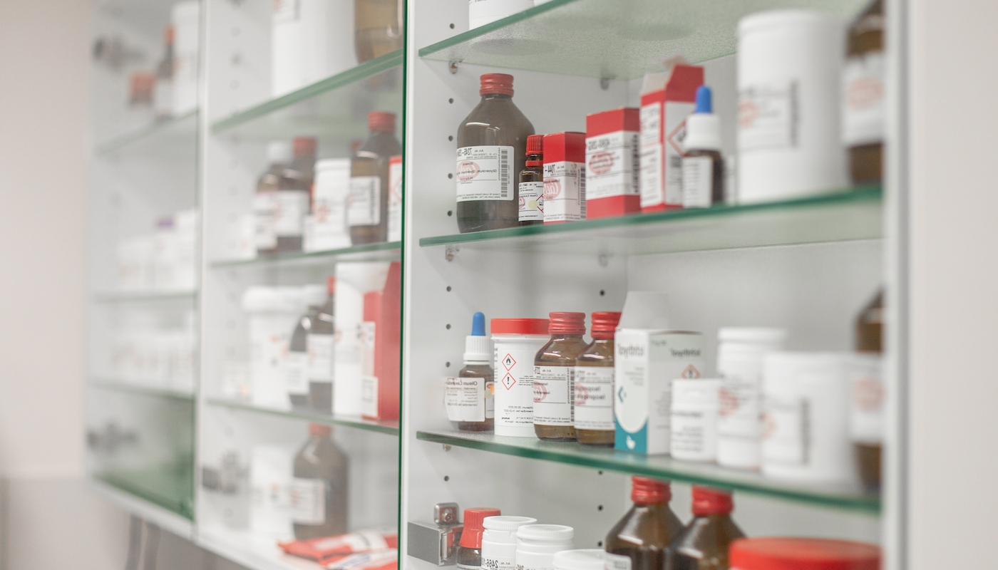 apothekSorgfältige Lagerung pharmazeutischer Produkte Ein Regal mit Glasfront zeigt sorgfältig geordnete Arzneimittel und pharmazeutische Produkte in einer Apotheke.